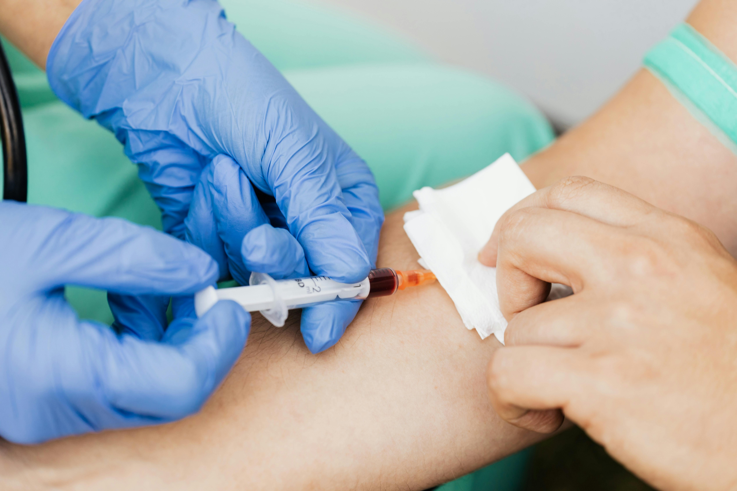 Close-up of a healthcare professional taking a blood sample using a syringe and gloves.